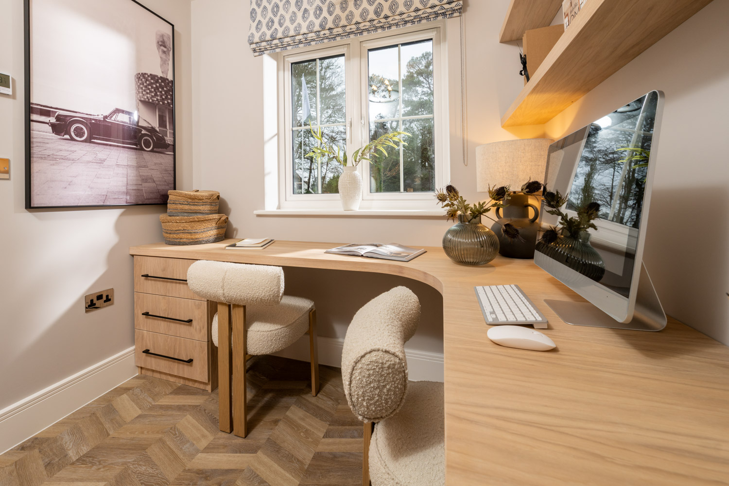 office with wooden desk and drawers and cream soft chairs with window and blind to the rear