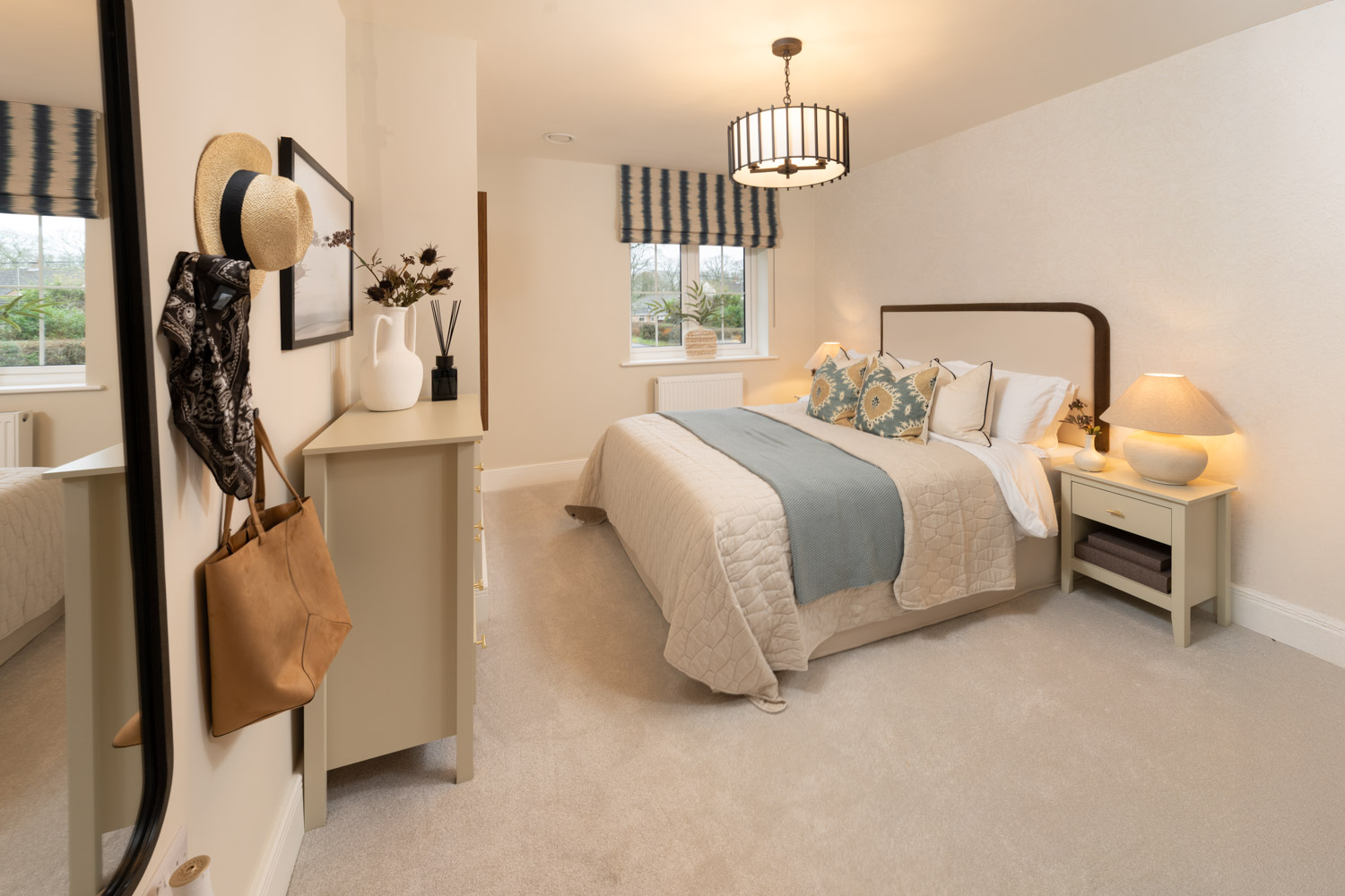 cream and blue bedroom with chest of drawers to the foot of the made up bed and window to the rear