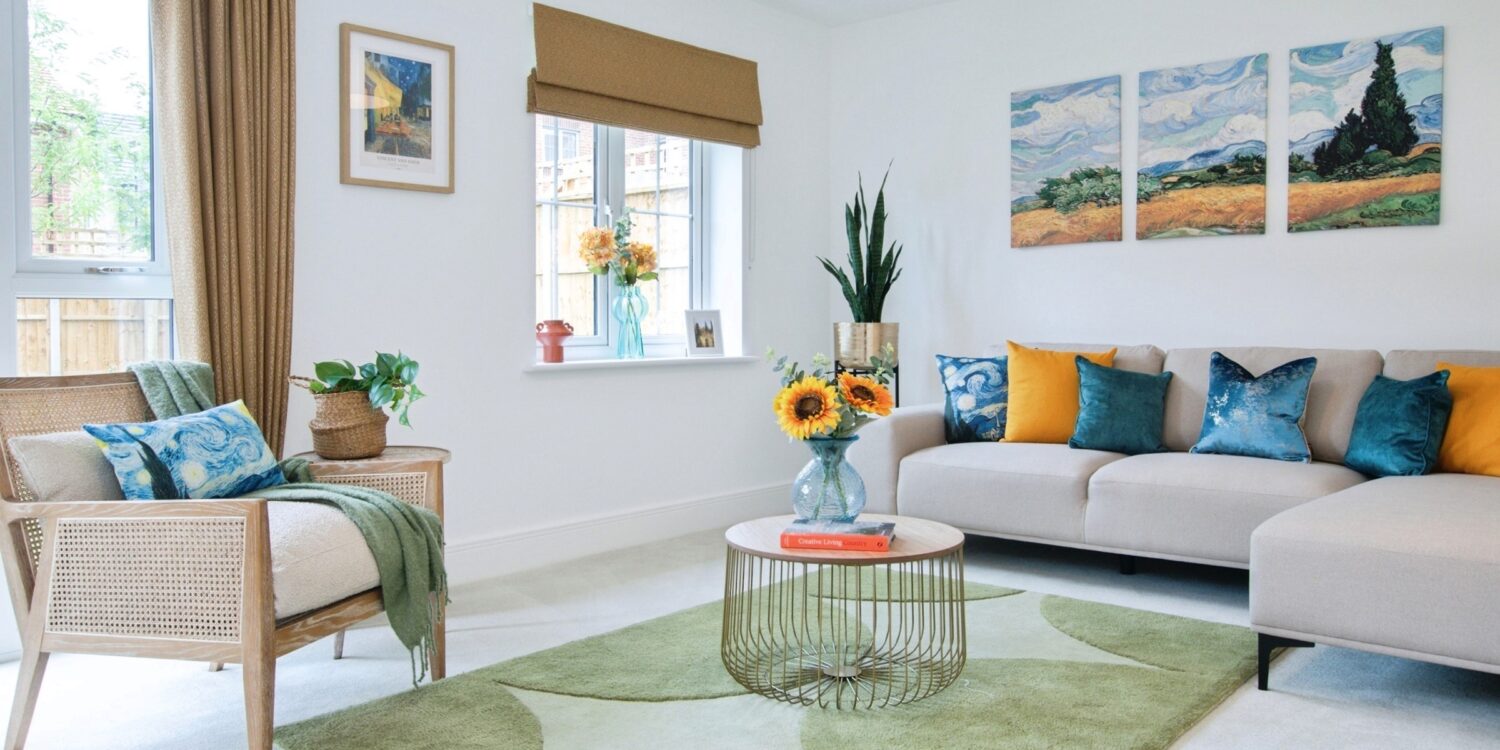 Living room with rug and central coffee table with sunflowers in a case and window in the background