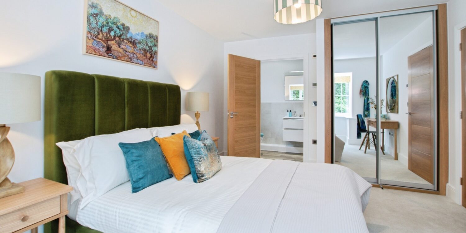 Bedroom with double bed and cushions with picture on the wall